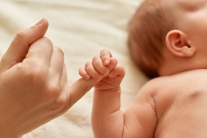 Ilustrasi bayi menggenggam jari orang dewasa—simbol kerentanan dan hak anak atas perlindungan sejak awal kehidupan.