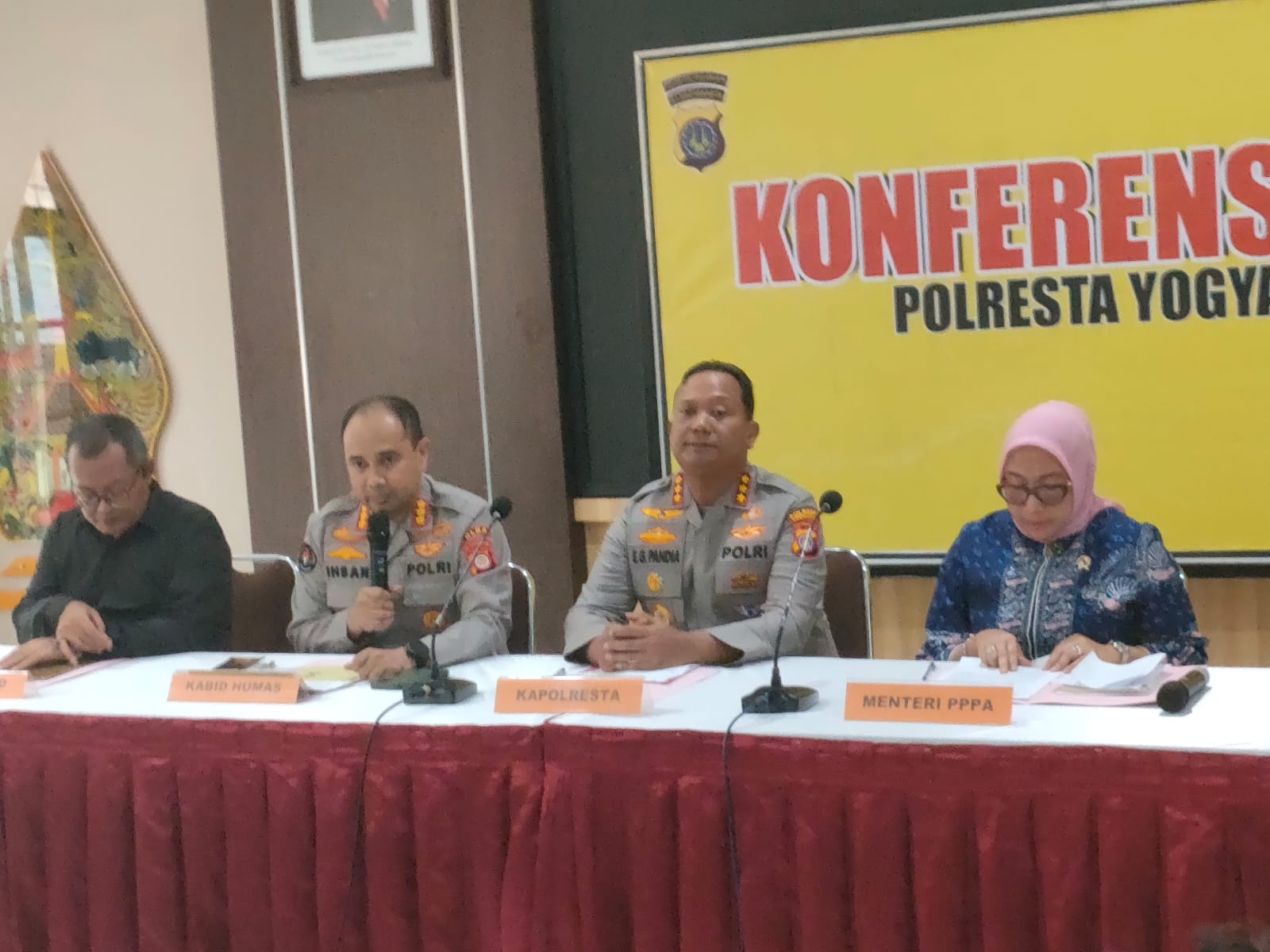 27day catrawarta Panel conference with three officials at a long table two police officers in uniform and a woman in hijab review documents Banner behind reads konferensi polresta yogyakarta