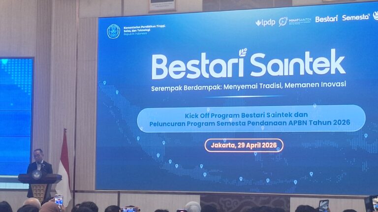 Speaker at a podium in front of a large blue conference banner reading 'Bestari Saintek' with event details, Indonesian flag visible on the left, and an audience in the foreground.