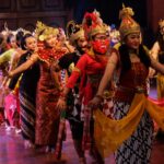Group of performers in elaborate traditional costumes and headdresses dancing on a stage festival