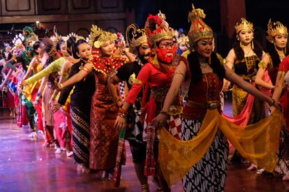 Group of performers in elaborate traditional costumes and headdresses dancing on a stage festival.