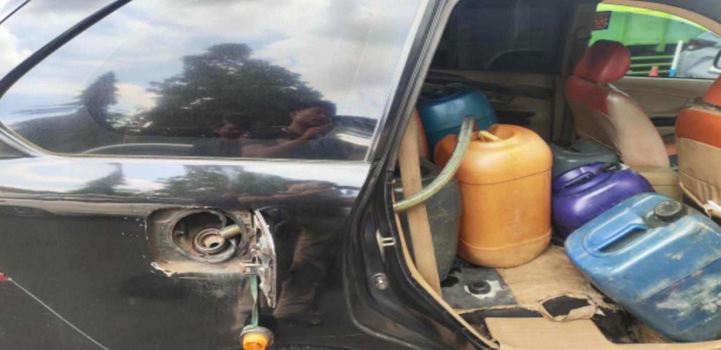 Open car door revealing several plastic gasoline containers orange purple blue occupying the back seat area the fuel filler is exposed on the side of the car