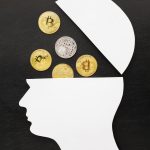 White cutout profile of a head with the top opened showing several bitcoin coins inside on a dark background
