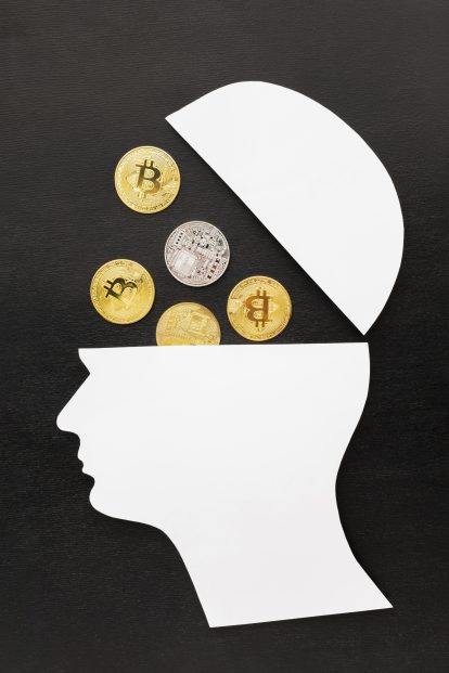 White cutout profile of a head with the top opened, showing several Bitcoin coins inside on a dark background.