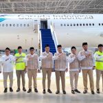 Group of garuda indonesia staff in uniforms posing in front of a plane inside a hangar