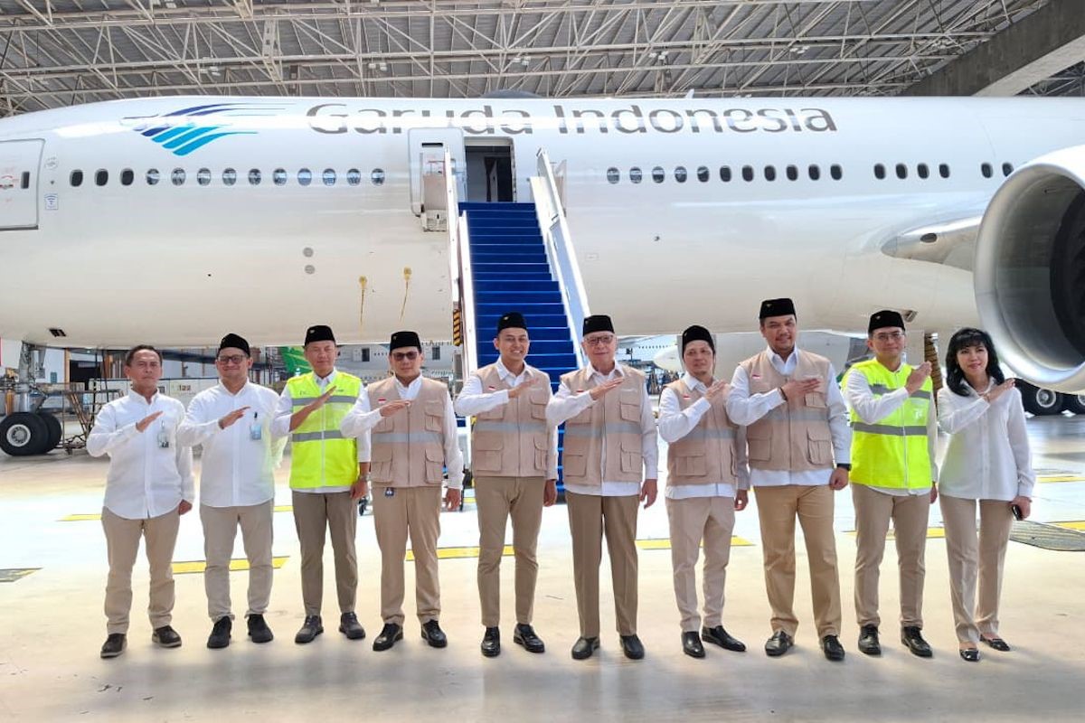 Group of garuda indonesia staff in uniforms posing in front of a plane inside a hangar