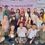 Group of students and teachers posing for a group photo in front of a pameran dewantara 2026 banner at an event venue all making hand signs