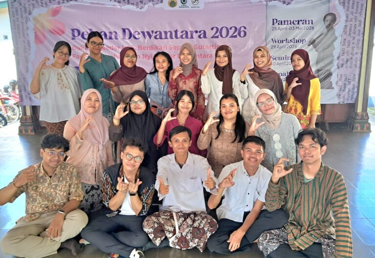 Group of students and teachers posing for a group photo in front of a Pameran Dewantara 2026 banner at an event venue, all making hand-signs.