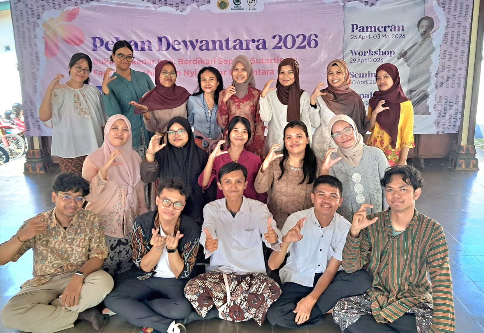 Img20260426wa0004 catrawarta Group of students and teachers posing for a group photo in front of a pameran dewantara 2026 banner at an event venue all making hand signs