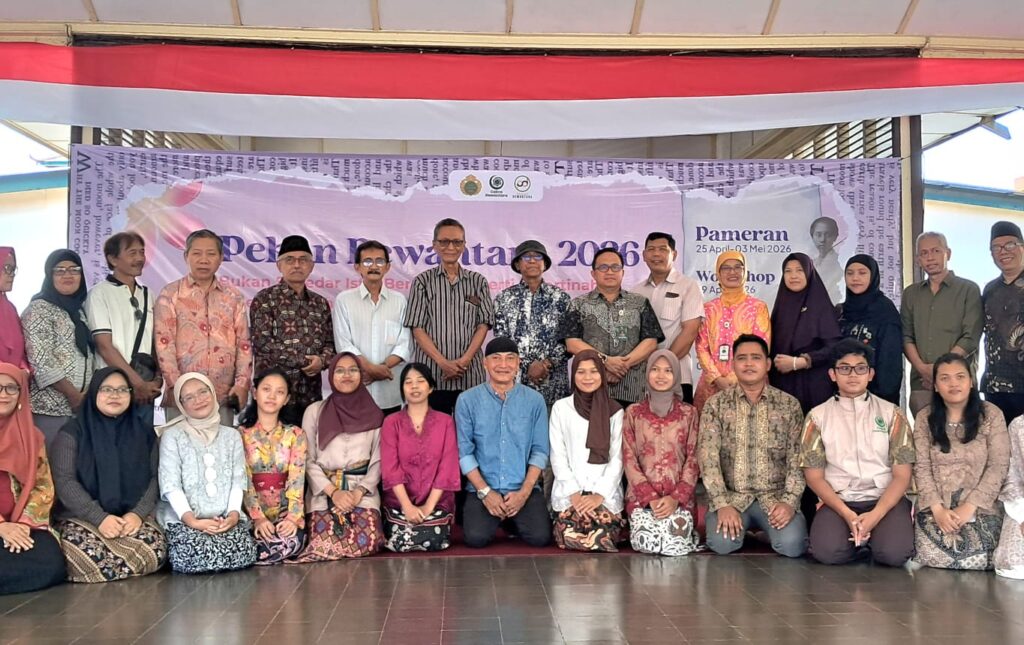 Img20260426wa0005 catrawarta Group of men and women in colorful traditional attire posing for a group photo on a stage with a banner behind them reading pameran 2026 and dates in indonesia