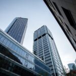 Low angle view of modern glass skyscrapers against a clear blue sky between surrounding buildings 12