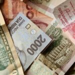Assorted banknotes from multiple currencies overlapping on a surface with varied designs and colors