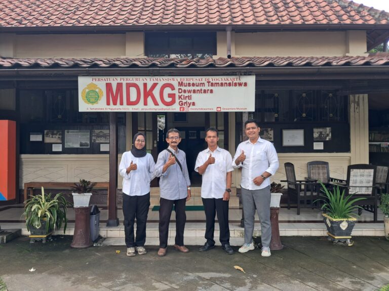 Four adults pose and give thumbs up in front of a museum entrance with a large MDKG banner reading 'Museum Tamansiswa' in Yogyakarta.] ,