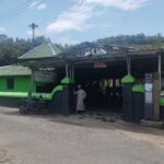 Entrance to a mosque with a green tiled roof worshippers remove their shoes before entering under a metal framed shelter