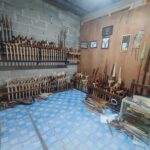 Workshop wall with rows of wooden handled carving chisels and knives on metal racks against a concrete block wall