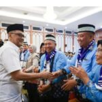 Man in white shirt shakes hands and greets a group of men in blue with scarves at a formal event smiles all around