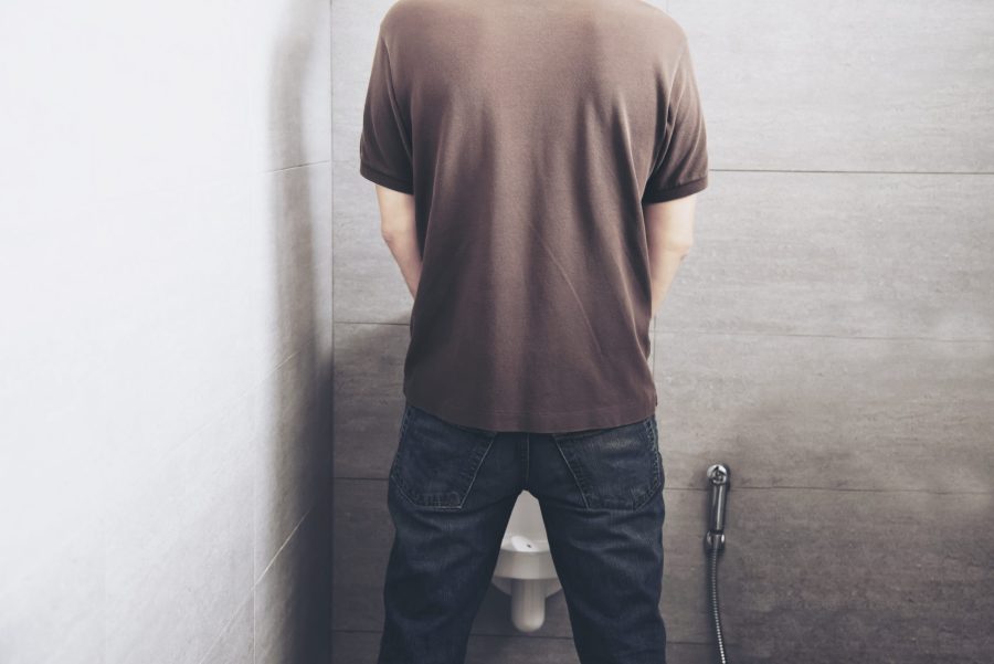 Man is standing pee in a toilet healthcare urinal concept catrawarta