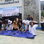 Officials and civilians destroy seized items on a blue tarp outside a police building during a evidence destruction event