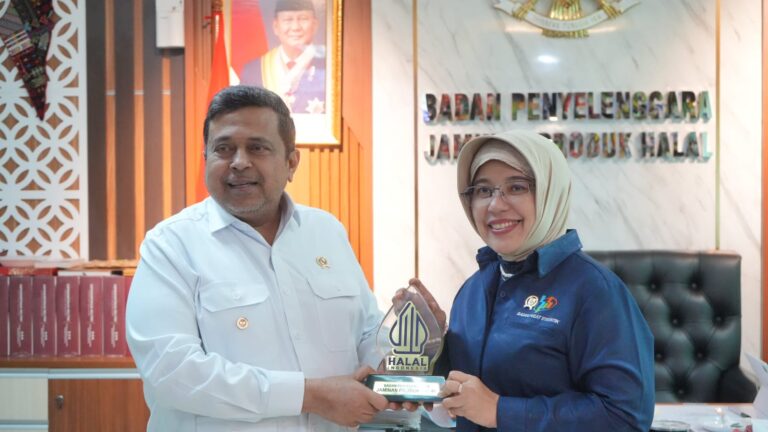 Man in a white shirt and a woman in a hijab pose with a Halal Indonesia trophy in an office setting.