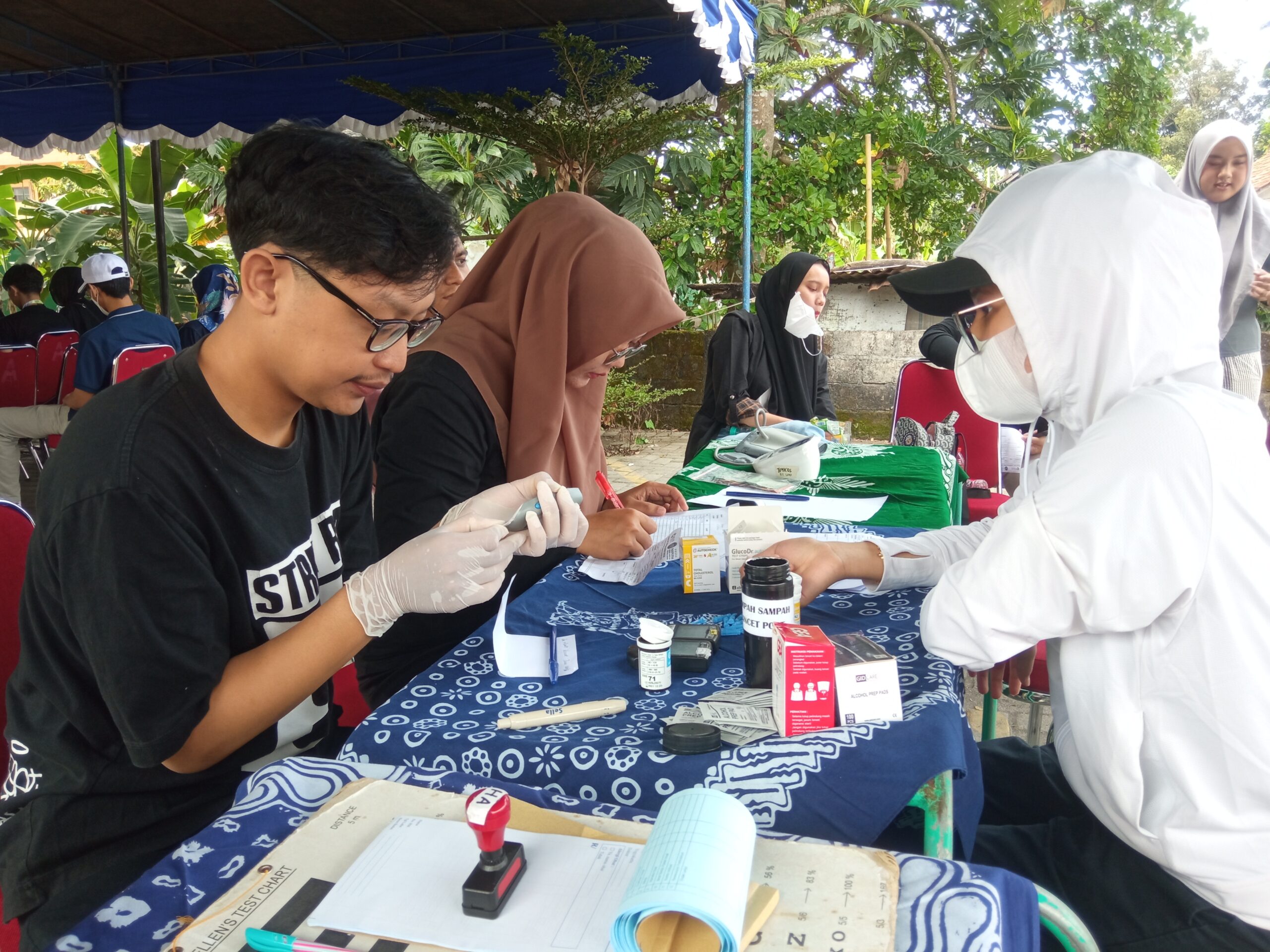 03walk catrawarta Outdoor medical screening station with a nurse in ppe and volunteers testing at a table under a canopy