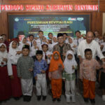 Group of students in uniforms and traditional outfits posing with officials at a ceremony titled peresmian revitalisasi