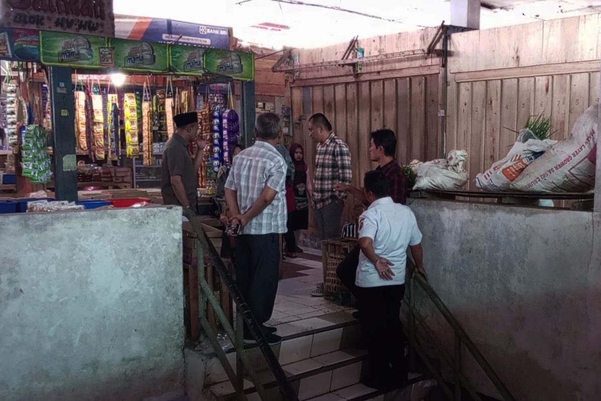 07pasar catrawarta Group of men standing on a stairwell in a busy market conversing near a shop with hanging dried snacks in view