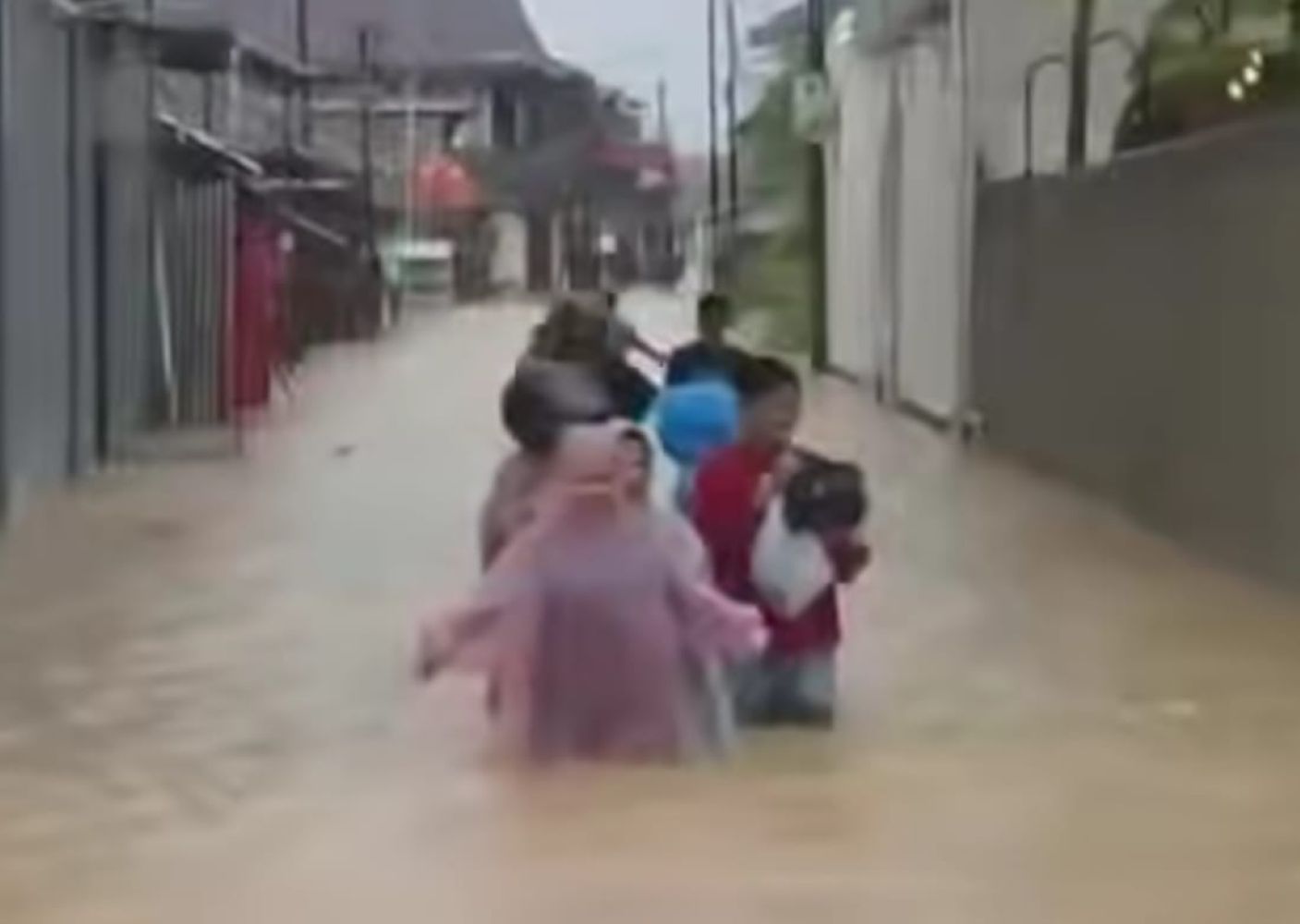 11ebanjir catrawarta People wading through knee deep floodwater on a residential street