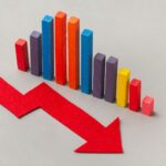 Colorful bar chart showing a downward trend with a large red arrow pointing downward across a light gray background
