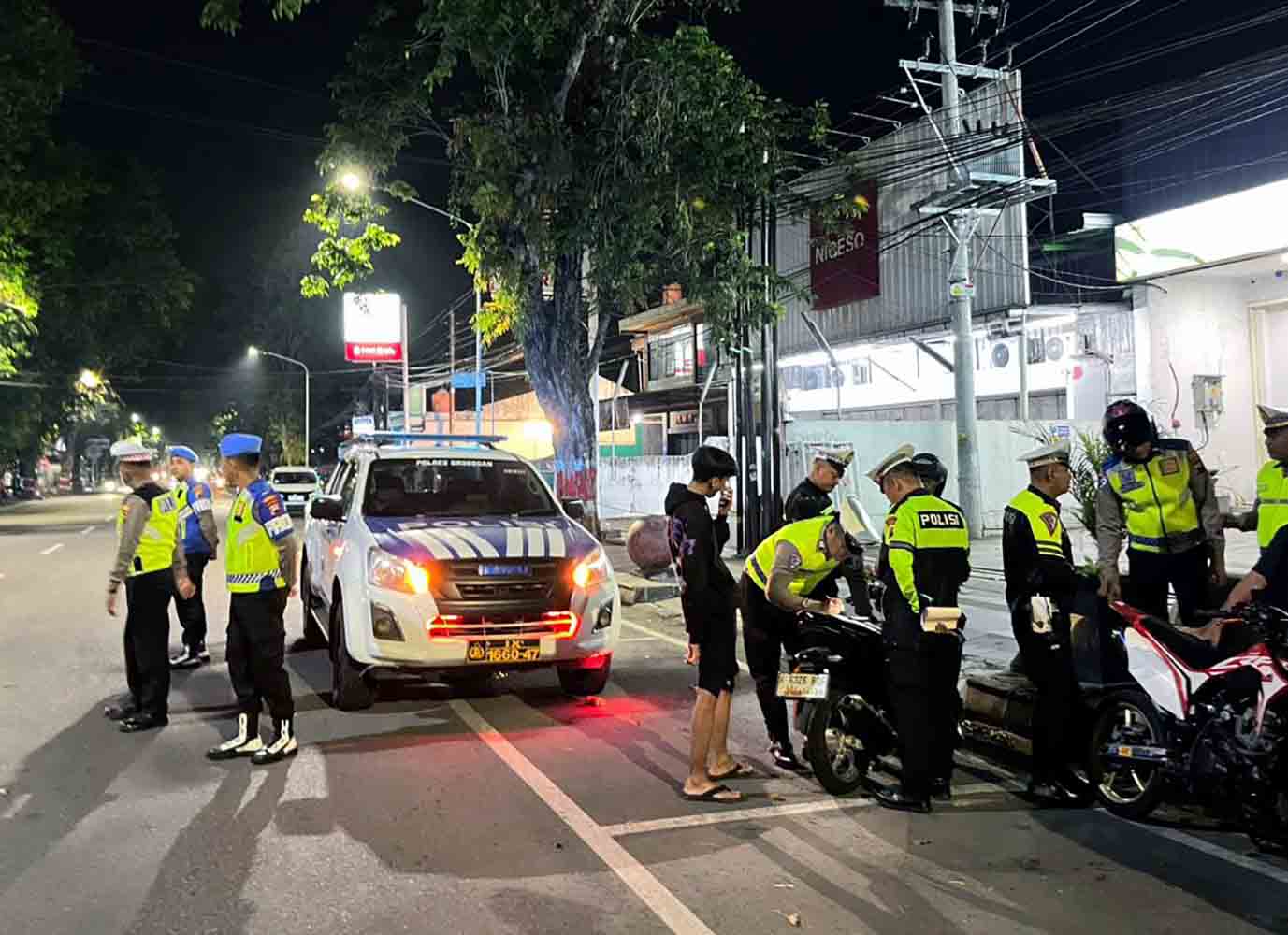 Nighttime traffic stop with police officers a marked police suv and motorbikes on a dimly lit street