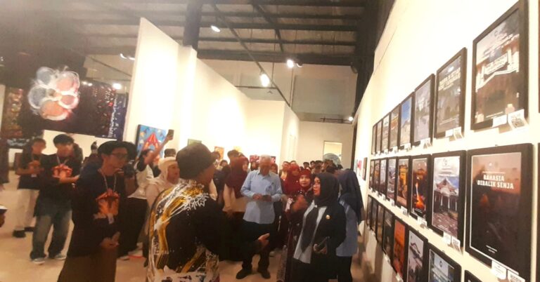 Crowd of people in a white-walled art gallery viewing framed posters on the wall.