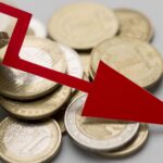 Coins spilling from a jar with a bold red downward arrow signaling a financial downturn or drop in value