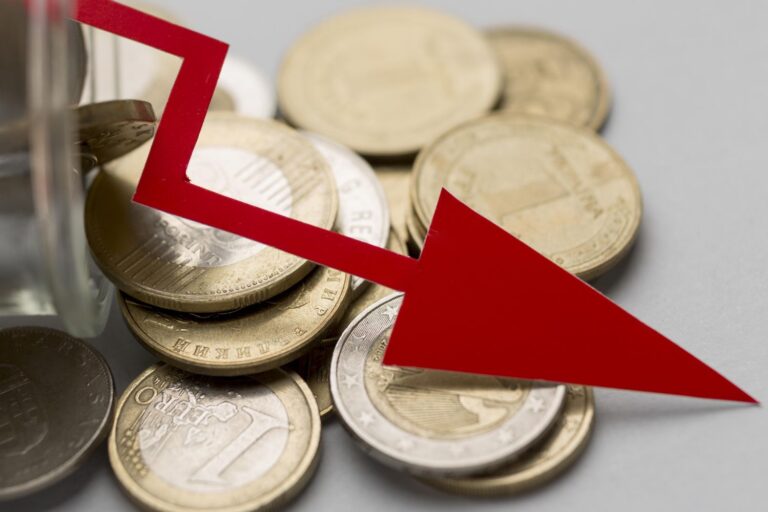 Coins spilling from a jar with a bold red downward arrow, signaling a financial downturn or drop in value