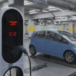 Blue electric car plugged into a charging station in a dim parking garage with another car in the background