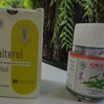 Boxes of herbal supplements calterol herbal and calcusol bottle on a table outdoors among greenery showing labels and logos