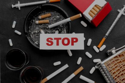 Card with the word stop resting on an ashtray filled with cigarette butts surrounded by pills syringes and a red cigarette packan anti substance abuse message