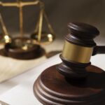Judges gavel in the foreground with the scales of justice blurred in the background symbolizing law and justice