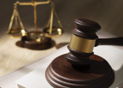Judge's gavel in the foreground with the scales of justice blurred in the background, symbolizing law and justice.