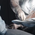 Surgeons in sterile gowns and gloves arranging surgical instruments on a tray during a operation