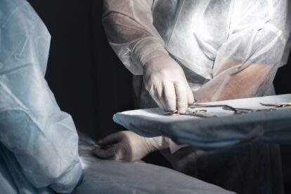 Surgeons in sterile gowns and gloves arranging surgical instruments on a tray during a operation.