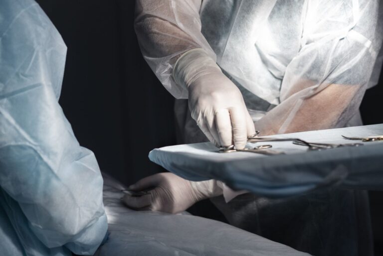 Surgeons in sterile gowns and gloves arranging surgical instruments on a tray during a operation.