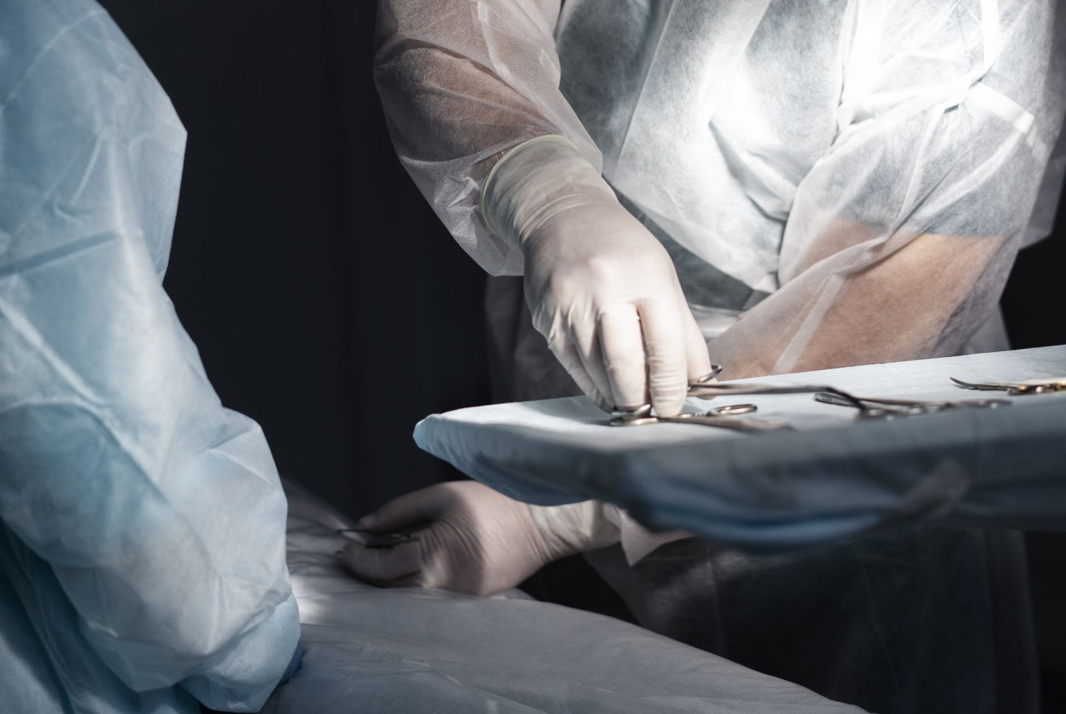 Surgeons in sterile gowns and gloves arranging surgical instruments on a tray during a operation
