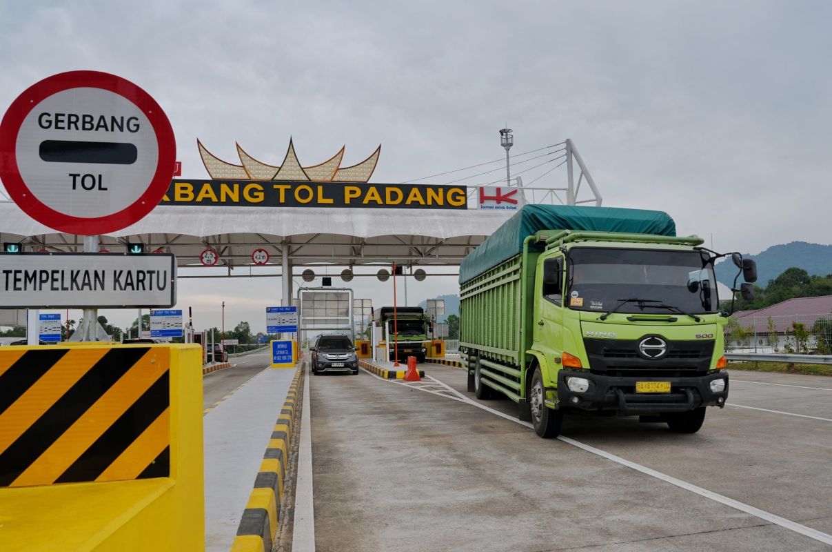 Green truck in the right lane at padang toll gate approaching toll booths beneath a large gerbang tol padang sign