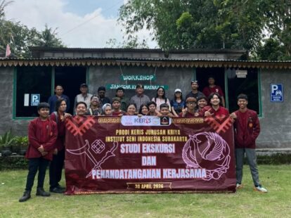 Group of students and instructors pose outdoors holding a maroon banner for a cooperation signing event at a workshop venue in Indonesia.