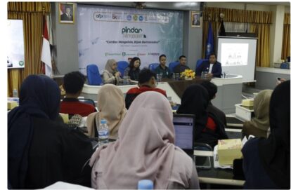 Panel discussion at a seminar: five speakers sit at a long table on a stage with a banner reading 'Pindar Belajar' behind them, audience seated in front.