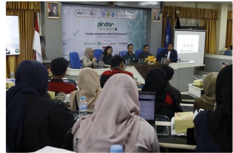 Panel discussion at a seminar: five speakers sit at a long table on a stage with a banner reading 'Pindar Belajar' behind them, audience seated in front.