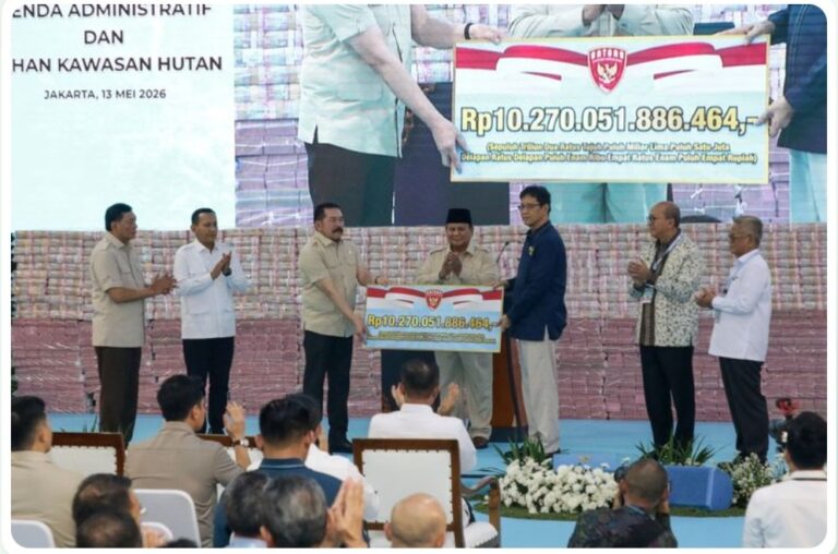 Officials on stage presenting a large ceremonial check to a man wearing a black cap as the audience applauds in front of a banner backdrop with Indonesian text, Rp10.270.051.886.464 shown on the check.