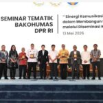 Twelve people on stage at a seminar each holding a plaque with a banner behind reading seminar tematik bakohumas dpr ri and the date 13 mei 2026