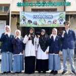 Six students in school uniforms pose with fists raised in front of a banner reading selamat hari bumi outside a building labeled man 2 yogyakarta