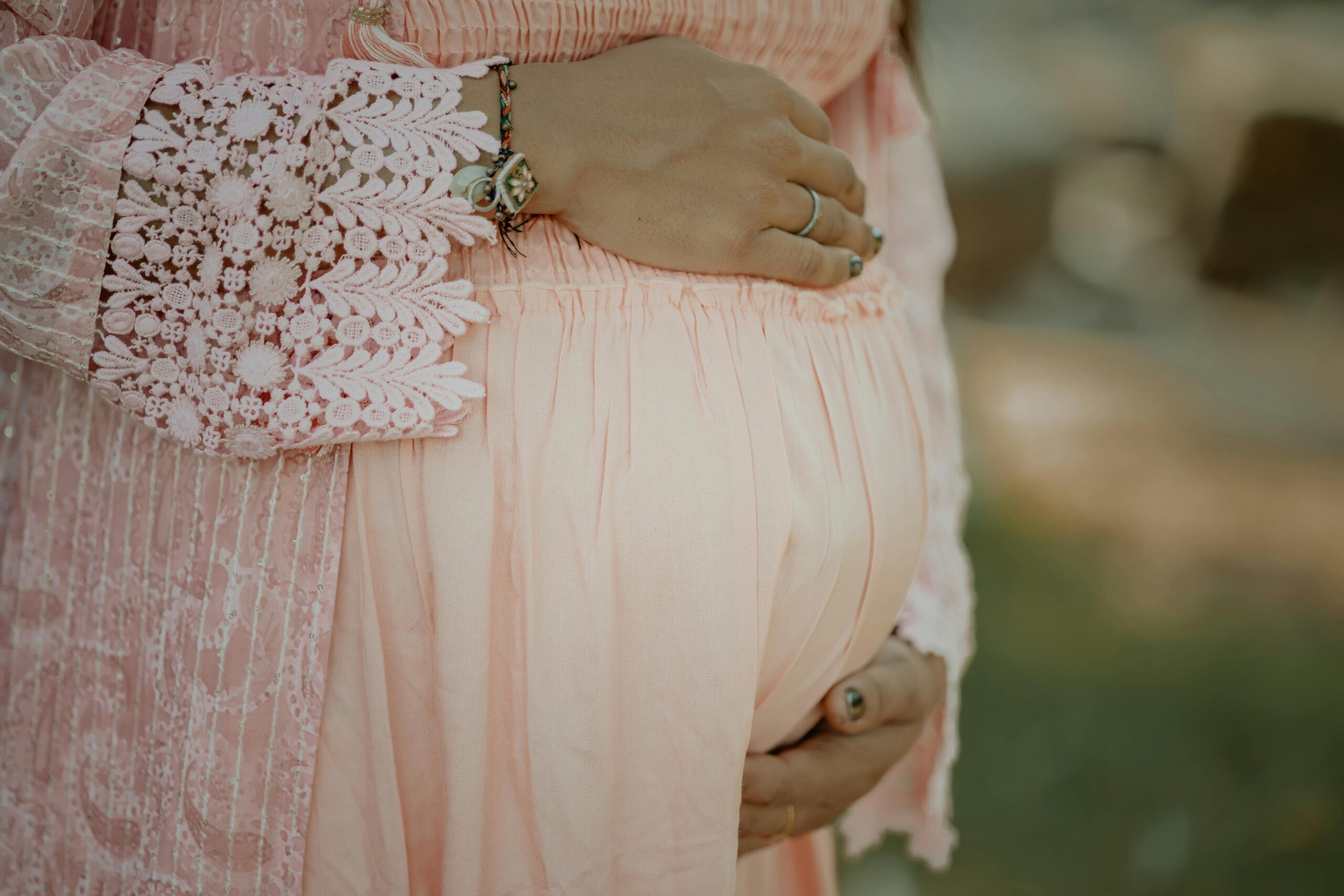 Pexelscameratreasure92892217704066 catrawarta Pregnant belly cradled by hands in a pink lace dress with rings visible on fingers