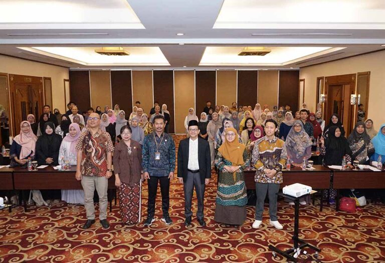 Group photo of conference attendees in a large meeting room, front row standing and others behind them